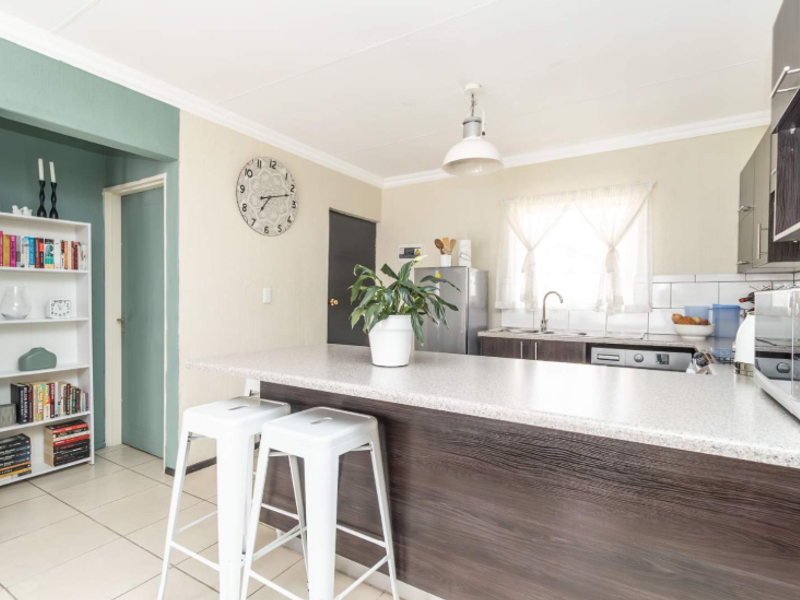 Open-plan kitchen featuring a breakfast bar, modern cabinetry, tiled flooring, and a functional layout connecting to the living area.