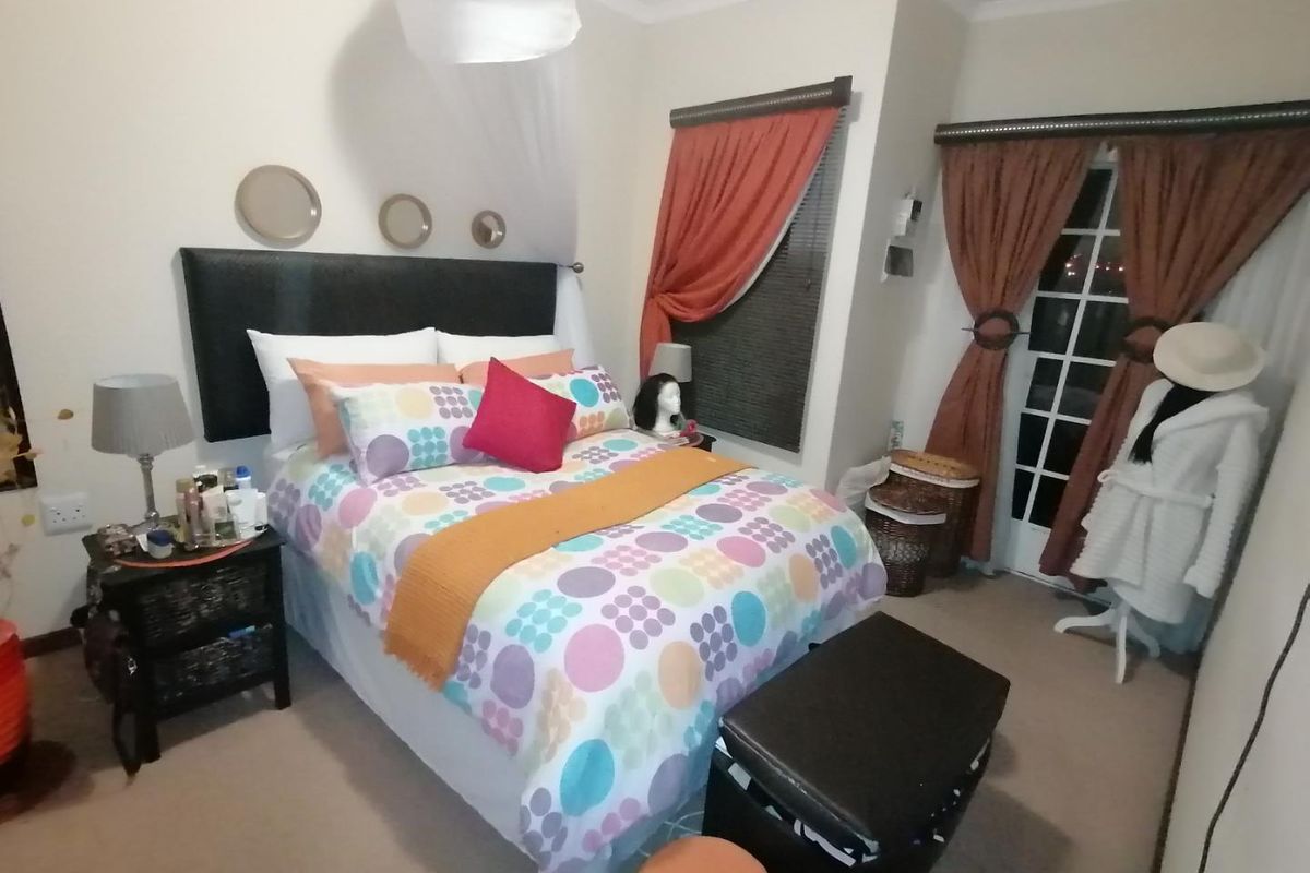 A cozy bedroom featuring carpeted flooring, a classic french door leading outside, and decorative coving detail.