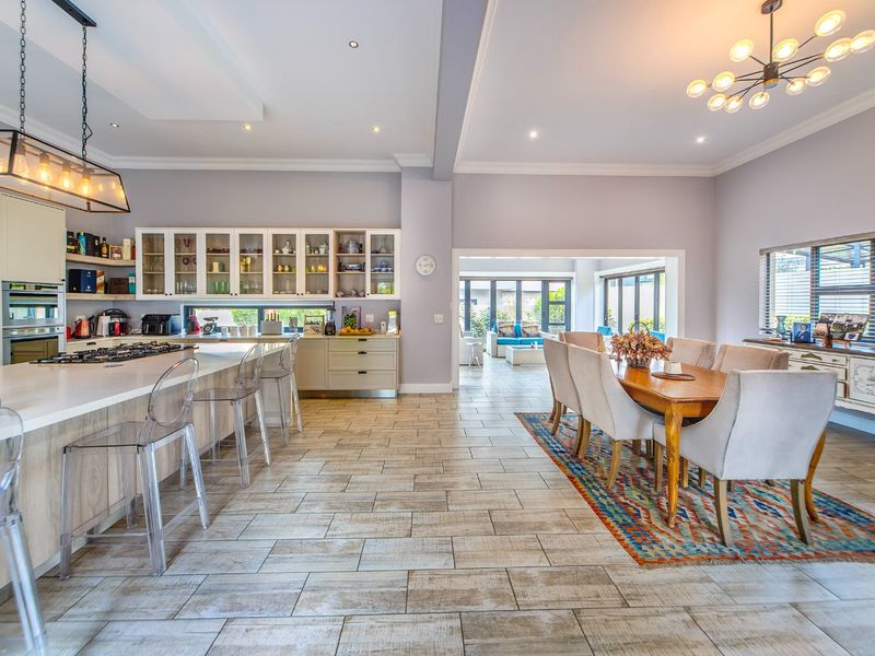 Spacious open-plan kitchen and dining area featuring a large island, modern cabinetry, tiled floors, and seamless flow to the adjacent living space.