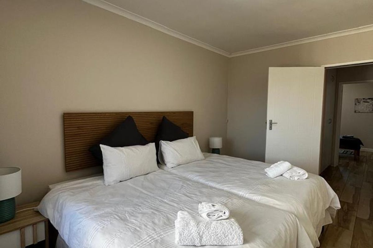 A well-maintained bedroom featuring wood-look tile flooring, a built-in headboard, and neutral wall finishes.