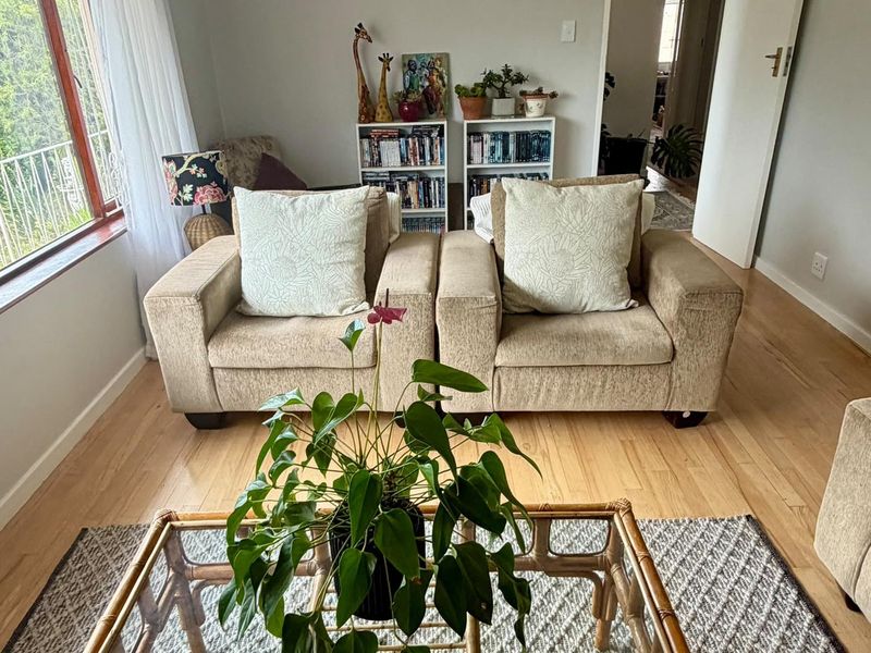 A bright living room featuring hardwood flooring and a large window, providing a comfortable and well-lit space.