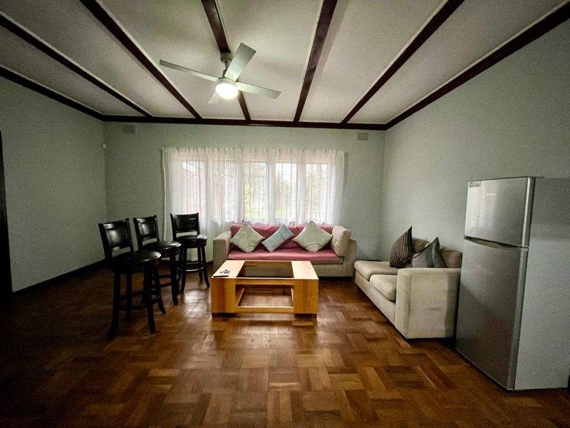 Spacious living area featuring classic parquet flooring, exposed timber ceiling beams, and a ceiling fan, offering a comfortable and traditional atmosphere.