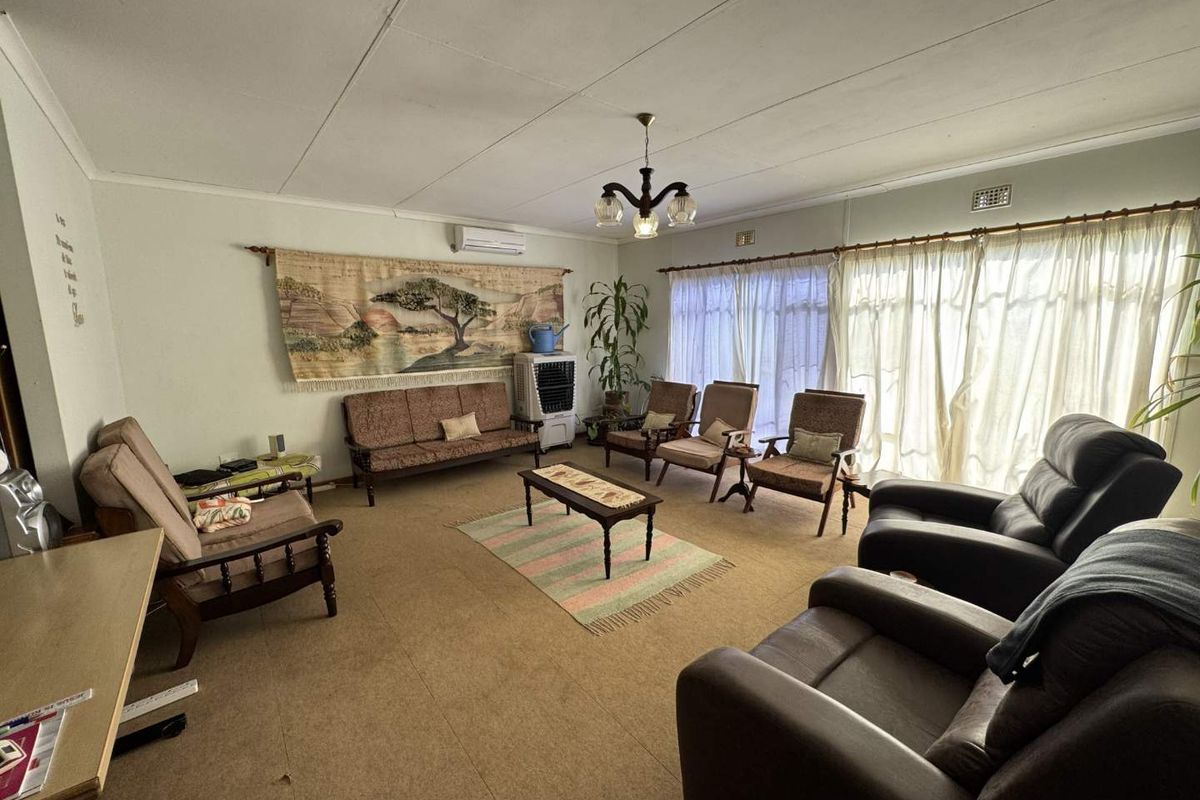 Spacious living room featuring a split-system air conditioner and large windows with curtain tracks, offering a functional layout ready for modernization.