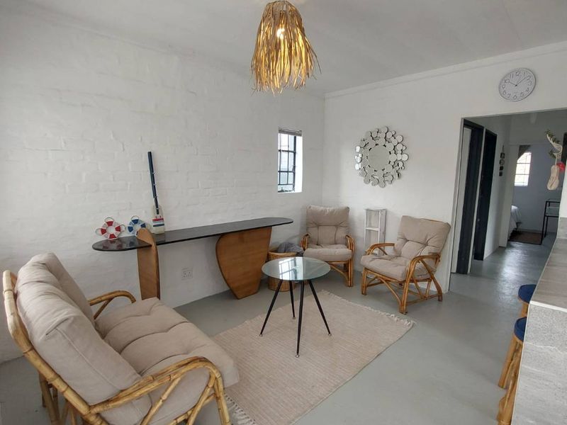 A bright living area featuring painted brick walls, a neutral concrete floor, and a central pendant light fixture, offering a clean and simple aesthetic.