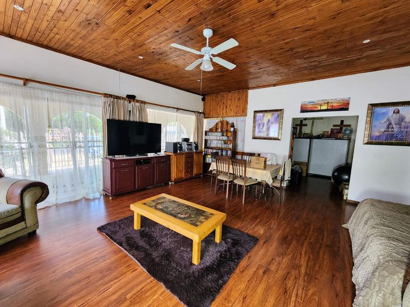 Spacious open-plan living and dining area featuring warm timber tongue and groove ceilings, laminate flooring, and large sliding doors providing natural light.
