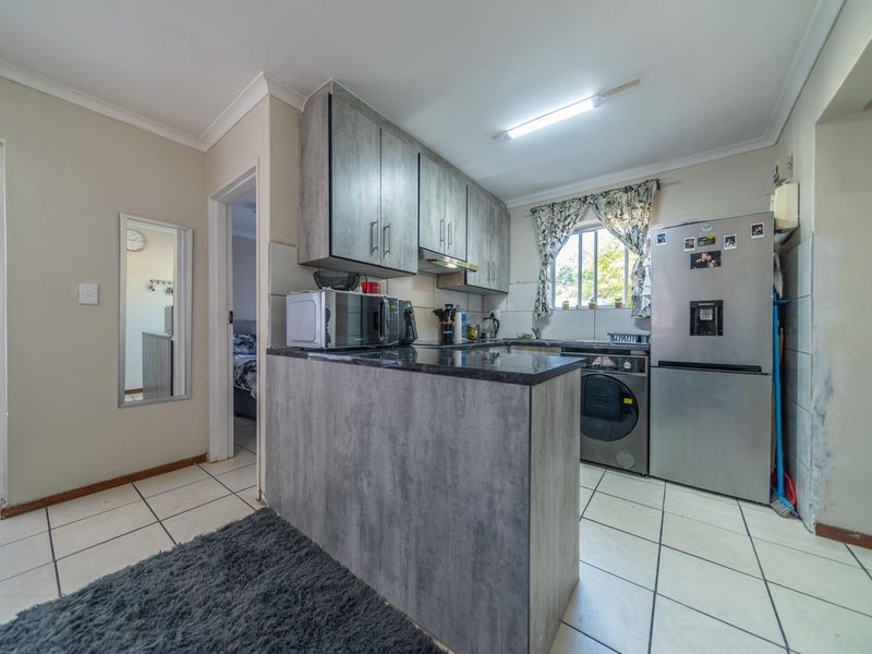 Compact kitchen featuring modern grey-toned cabinetry, stone-look countertops, tiled flooring, and an integrated extractor fan, offering a functional layout for apartment living.