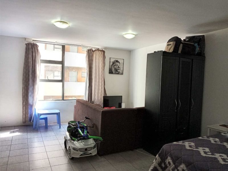 A bedroom featuring tiled flooring and a large window providing natural light, with flush mount ceiling lighting.