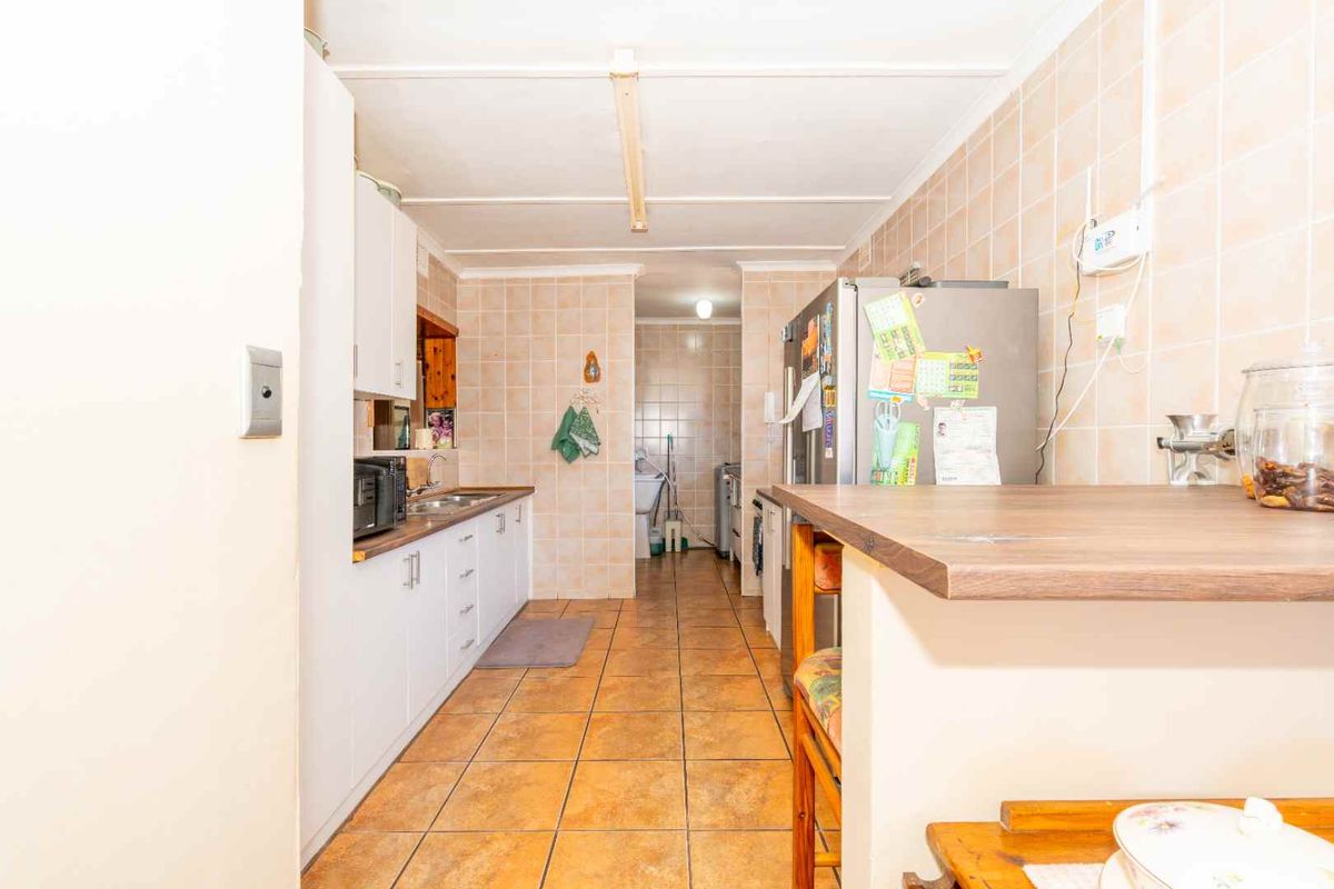 A functional kitchen featuring tiled walls and flooring, built-in cabinetry, and a laminate countertop, offering a dated aesthetic ready for modernization.