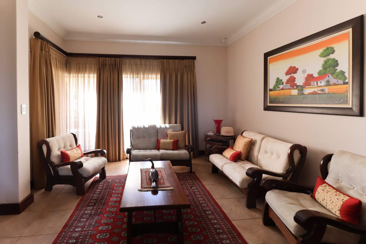 A comfortable living room featuring tiled flooring, recessed ceiling lighting, and large windows with floor-to-ceiling curtains providing natural light.