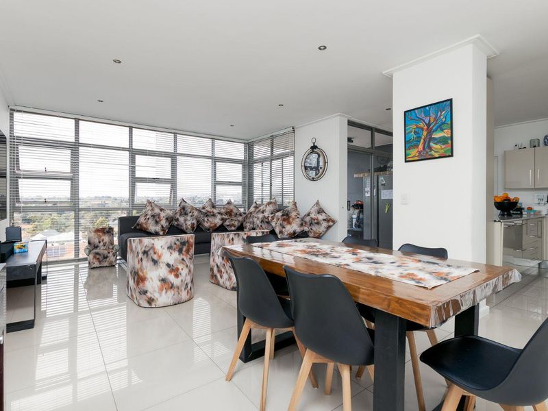 Spacious open-plan living and dining area featuring large windows with natural light, tiled floors, and a modern integrated kitchen.
