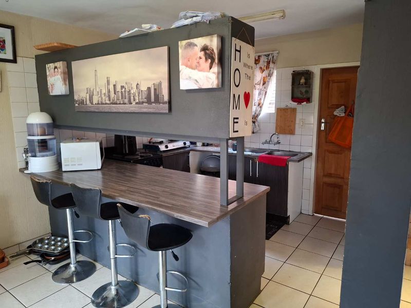 A compact kitchen featuring a breakfast bar, tiled flooring, and built-in cabinetry with a tiled backsplash.