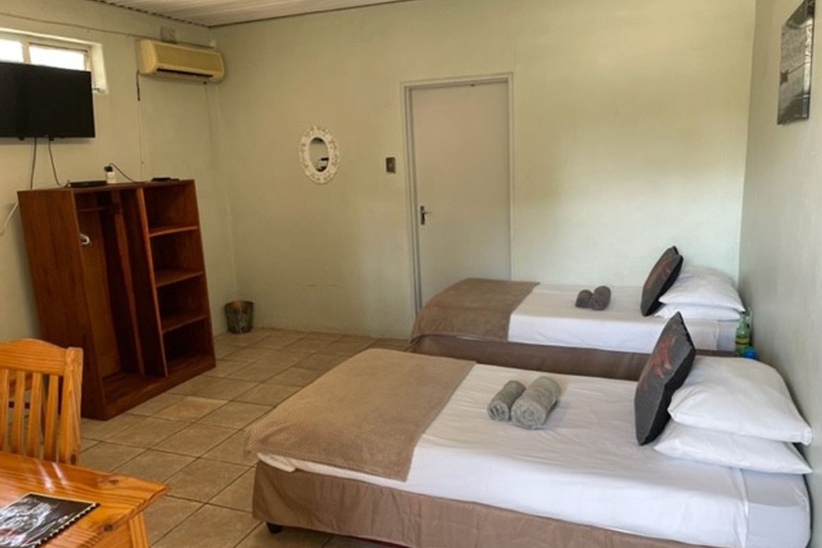 A functional bedroom featuring tiled flooring, a corrugated metal ceiling, and a wall-mounted air conditioning unit.