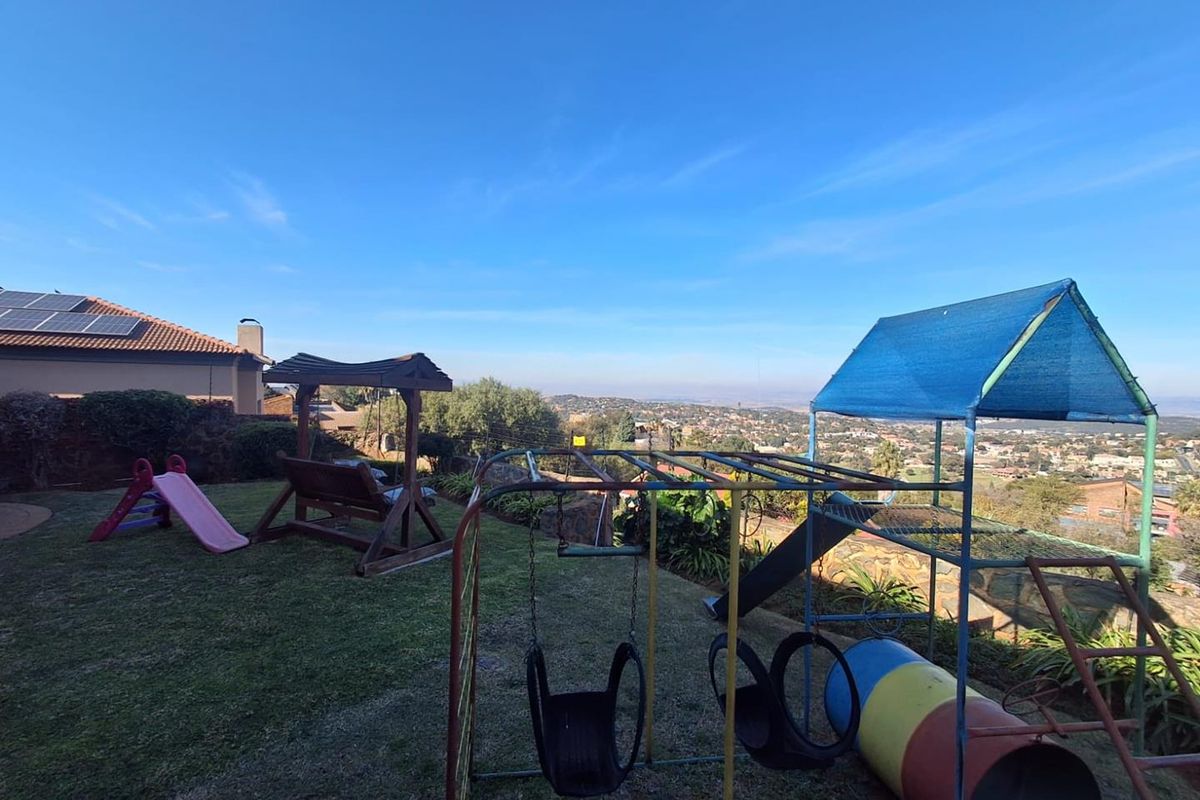 A spacious rear garden area featuring a lawn, established landscaping, and expansive elevated views over the surrounding neighborhood.