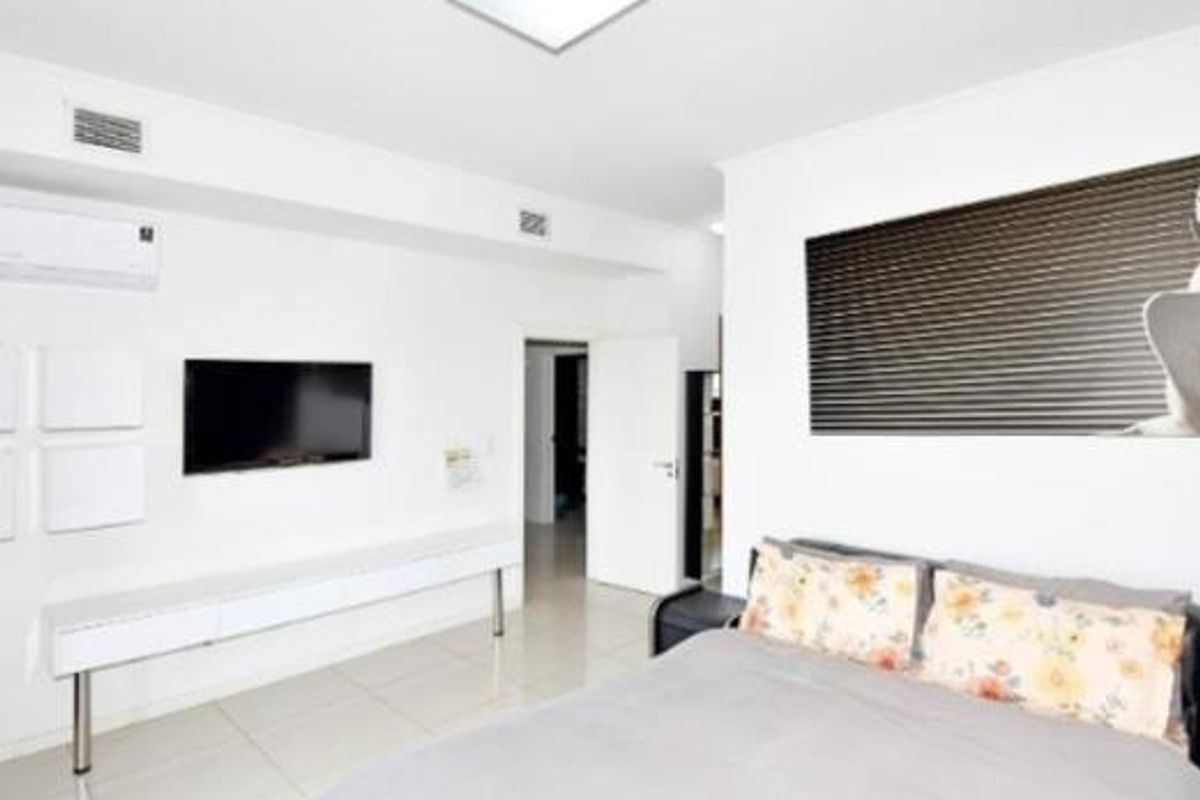 A bright bedroom featuring tiled flooring, built-in wall shelving, and an integrated air conditioning unit.