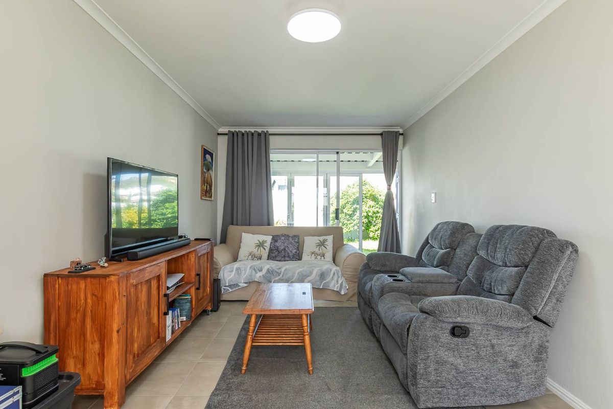 A comfortable living room featuring tiled flooring, a flush mount ceiling light, and a sliding glass door providing access to the outdoor area.