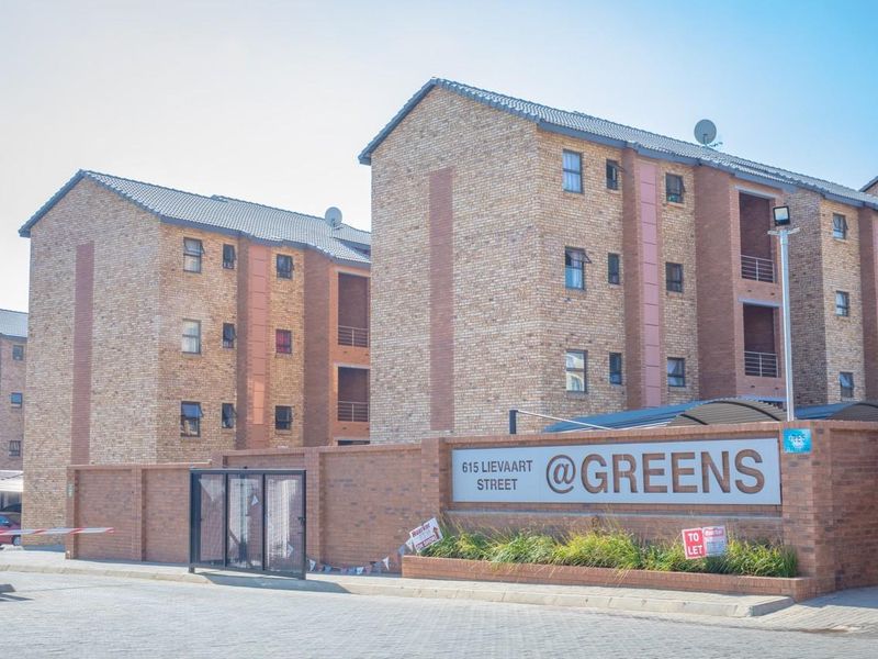Exterior view of the apartment complex entrance featuring face brick buildings, secure perimeter wall, and gated access.