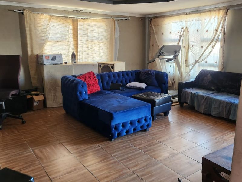 Living room featuring tiled flooring and a recessed ceiling design, currently requiring wall finishing and cosmetic updates to improve the overall aesthetic.