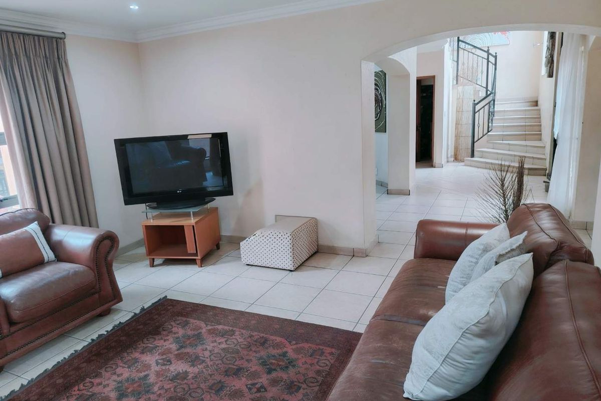 A living room featuring tiled flooring, an arched entryway leading to a staircase, and recessed ceiling lighting.