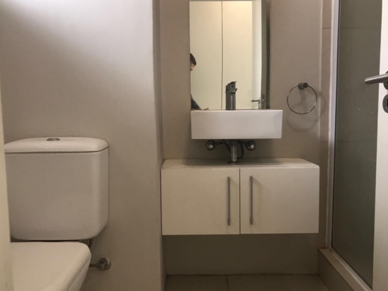 A clean, modern bathroom featuring a wall-mounted vanity with a vessel sink, a toilet, and a glass-enclosed shower area.
