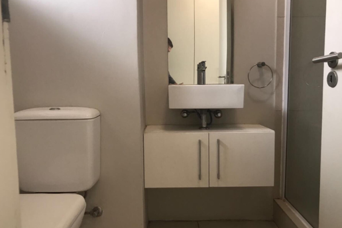 A clean, modern bathroom featuring a wall-mounted vanity with a vessel sink, a toilet, and a glass-enclosed shower area.