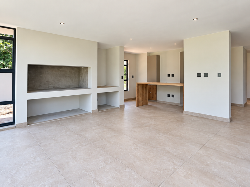 Spacious open-plan living area featuring large glass sliding doors, tiled flooring, a built-in fireplace, and a modern breakfast bar counter.
