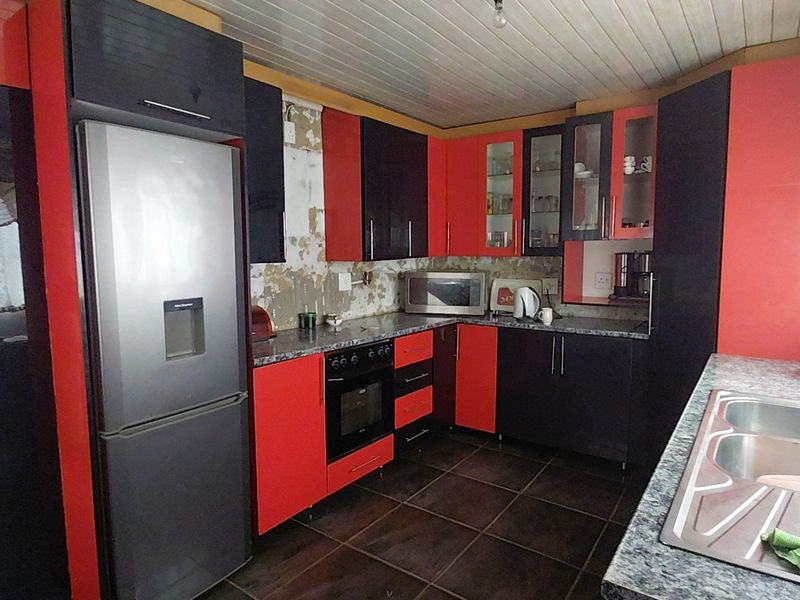 Kitchen featuring high-contrast cabinetry, laminate countertops, and a double bowl sink. The space requires wall repairs and cosmetic updates to improve functionality and aesthetic appeal.