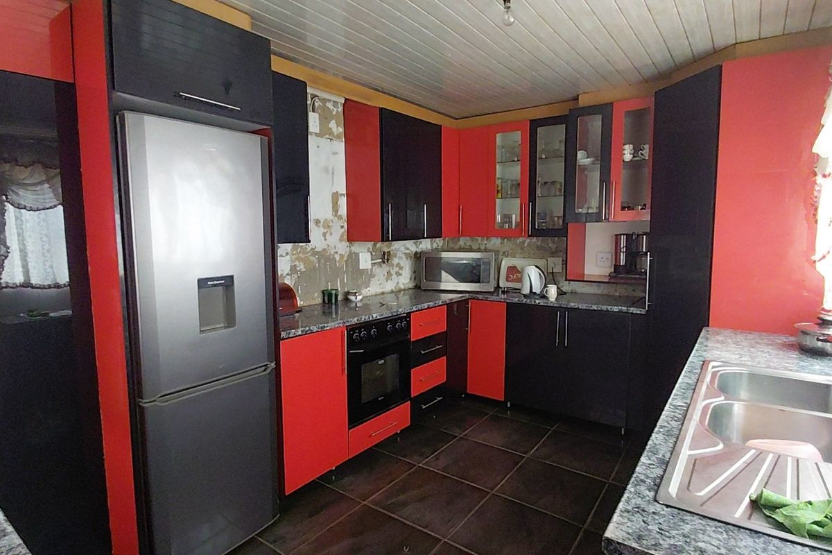Kitchen featuring high-contrast cabinetry, laminate countertops, and a double bowl sink. The space requires wall repairs and cosmetic updates to improve functionality and aesthetic appeal.
