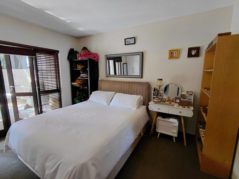 A bedroom featuring neutral walls, carpeted flooring, and a sliding glass door with venetian blinds providing access to the exterior.