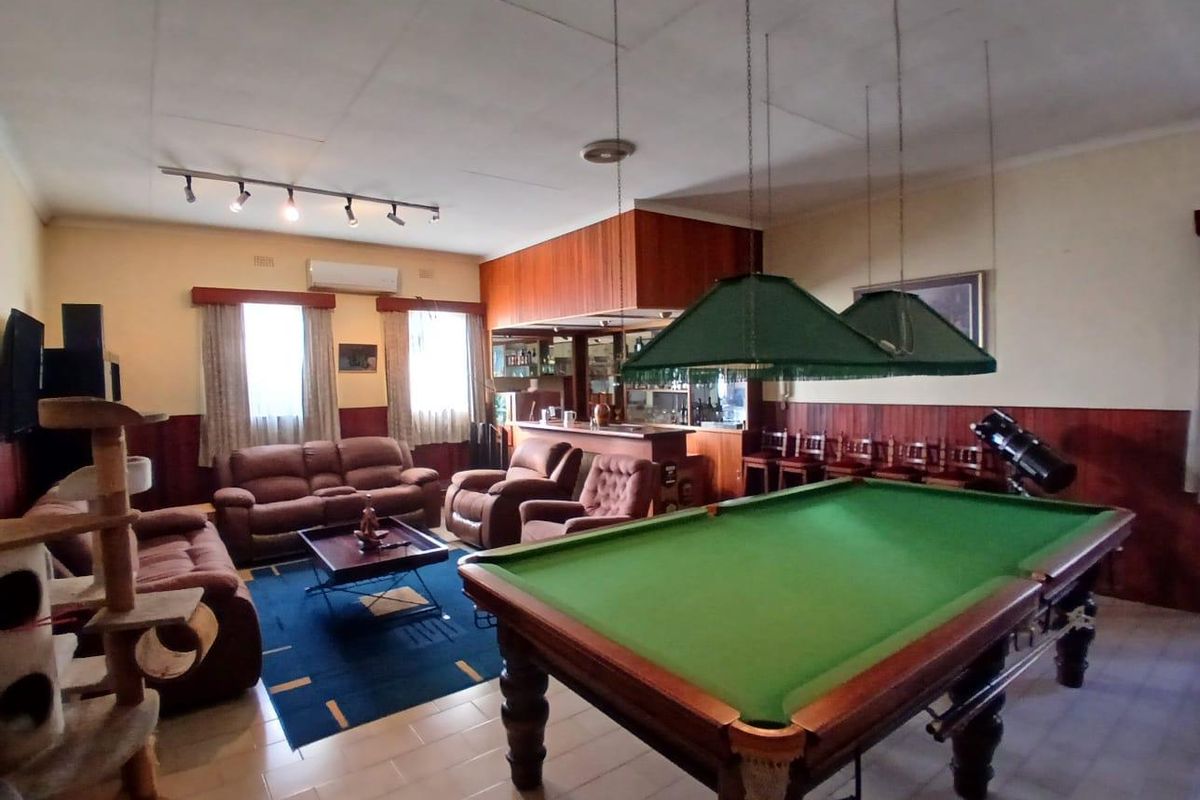 Spacious living area featuring a built-in bar, wood paneling, and dedicated space for entertainment, including a pool table and lounge area.