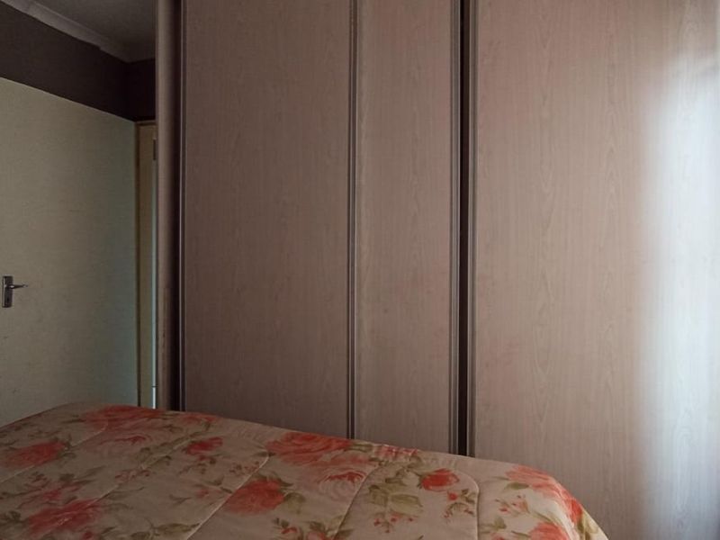 A bedroom featuring a large built-in wardrobe with light wood-grain finish doors.