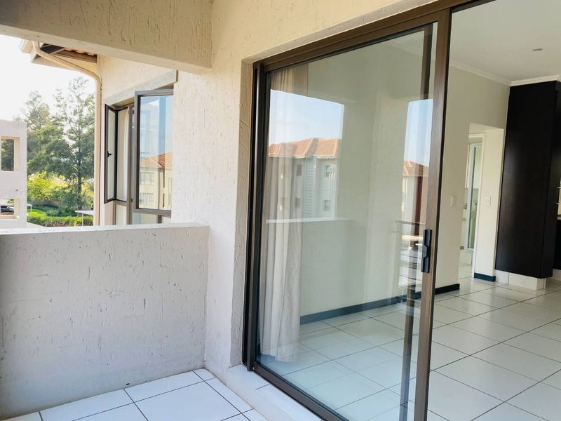 A covered balcony featuring tiled flooring and a large sliding glass door providing access to the interior living space.
