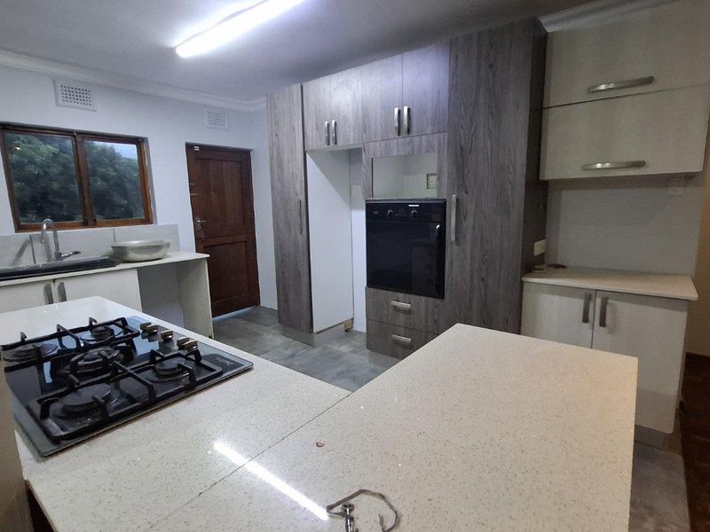 Modern kitchen featuring stone countertops, a gas hob, built-in oven, and ample cabinetry, currently awaiting final finishing touches.