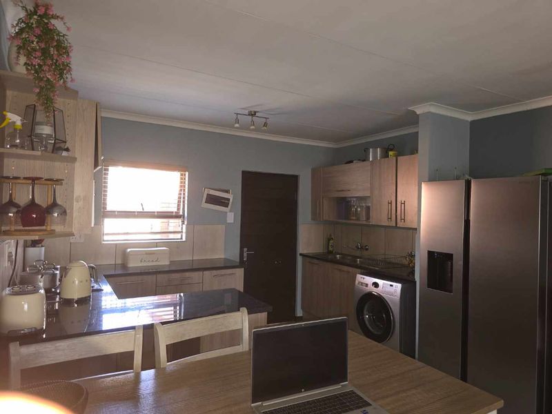 A functional kitchen featuring wood-finish cabinetry, granite countertops, a tiled backsplash, and integrated appliance spaces, offering a practical layout for daily use.