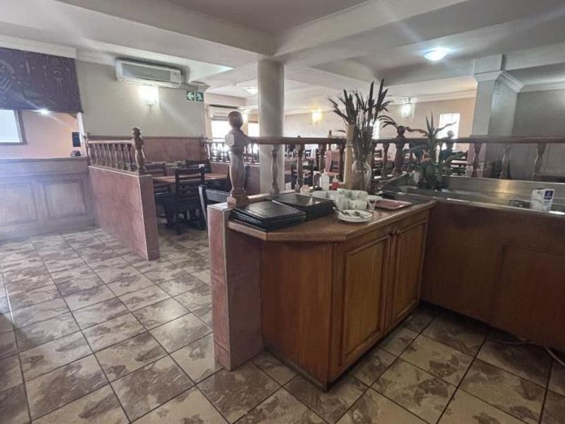 Open-plan commercial dining area featuring tiled flooring, built-in service cabinetry, and a wooden balustrade partition, suitable for restaurant or hospitality use.