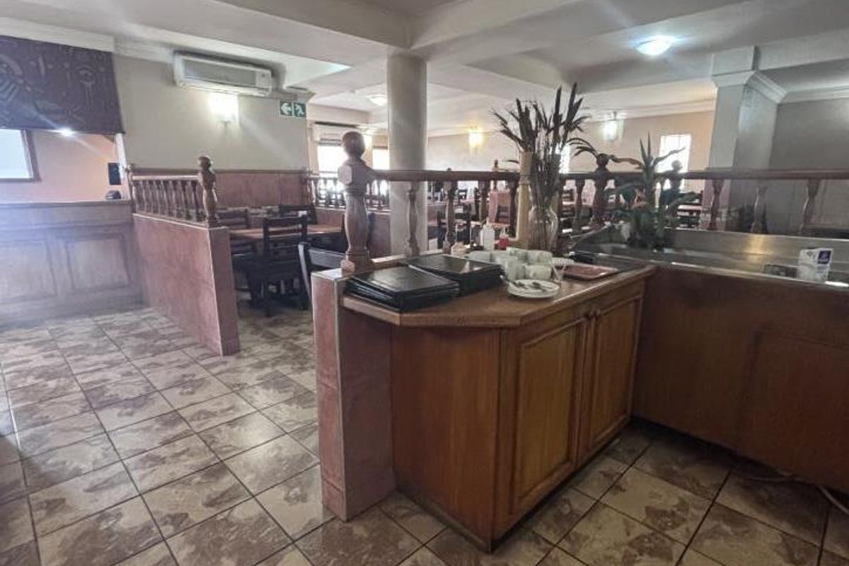 Open-plan commercial dining area featuring tiled flooring, built-in service cabinetry, and a wooden balustrade partition, suitable for restaurant or hospitality use.