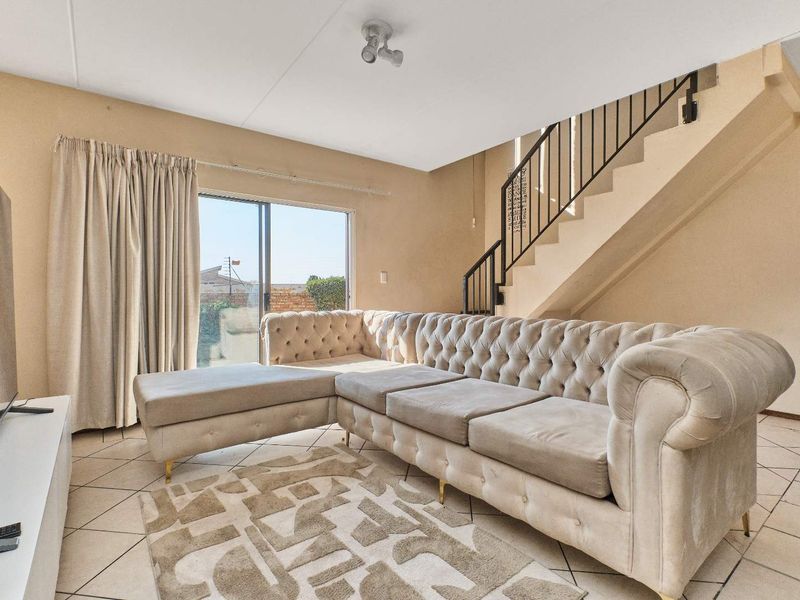 A living room featuring tiled flooring, a staircase with a metal railing, and a sliding glass door providing access to the exterior.