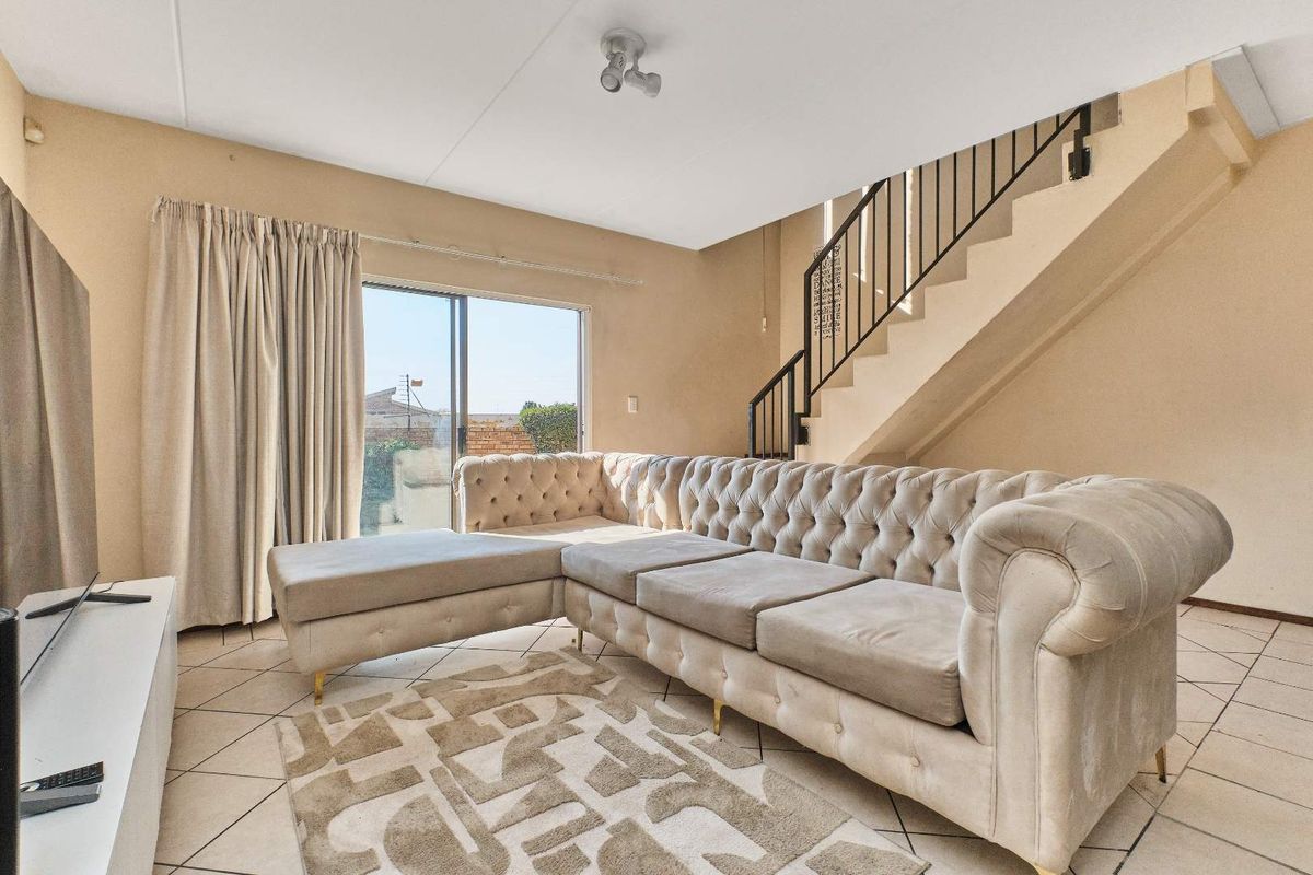 A living room featuring tiled flooring, a staircase with a metal railing, and a sliding glass door providing access to the exterior.