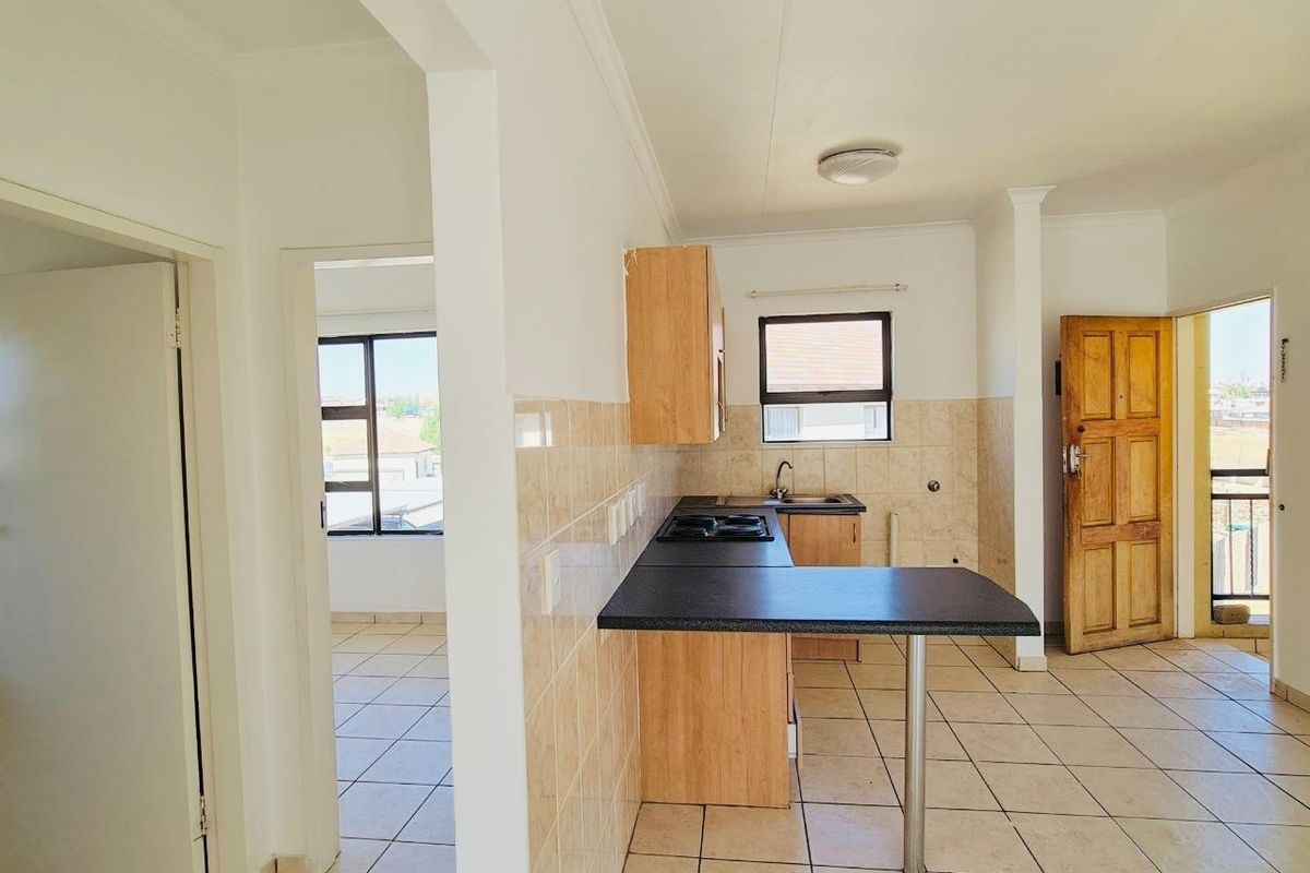 A functional kitchen area featuring a breakfast bar, built-in cabinetry, and tiled flooring, seamlessly connected to the adjacent living space.