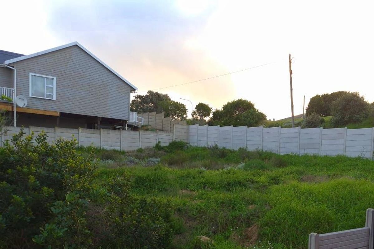 A view of a vacant residential plot featuring a precast concrete boundary wall and adjacent residential property.