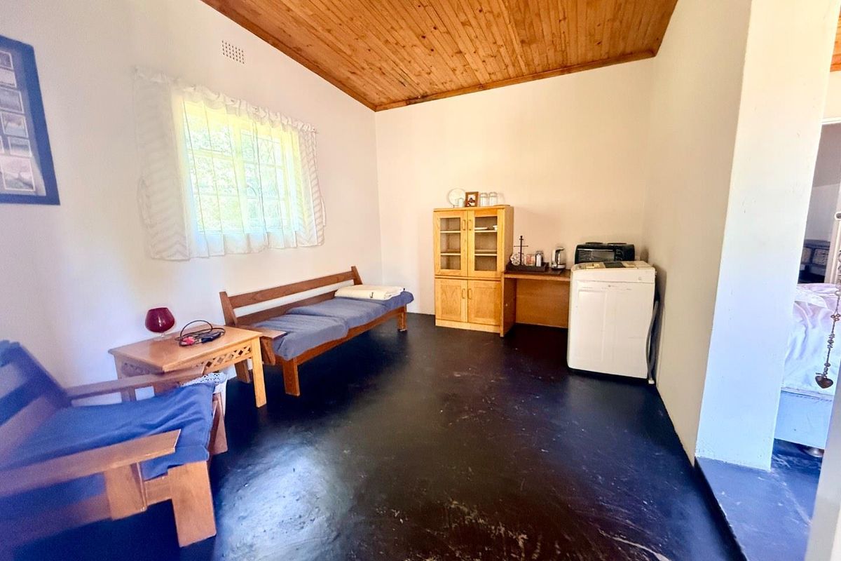 A multi-purpose room featuring a timber-clad ceiling, dark painted flooring, and a window with natural light, suitable for various living or utility configurations.