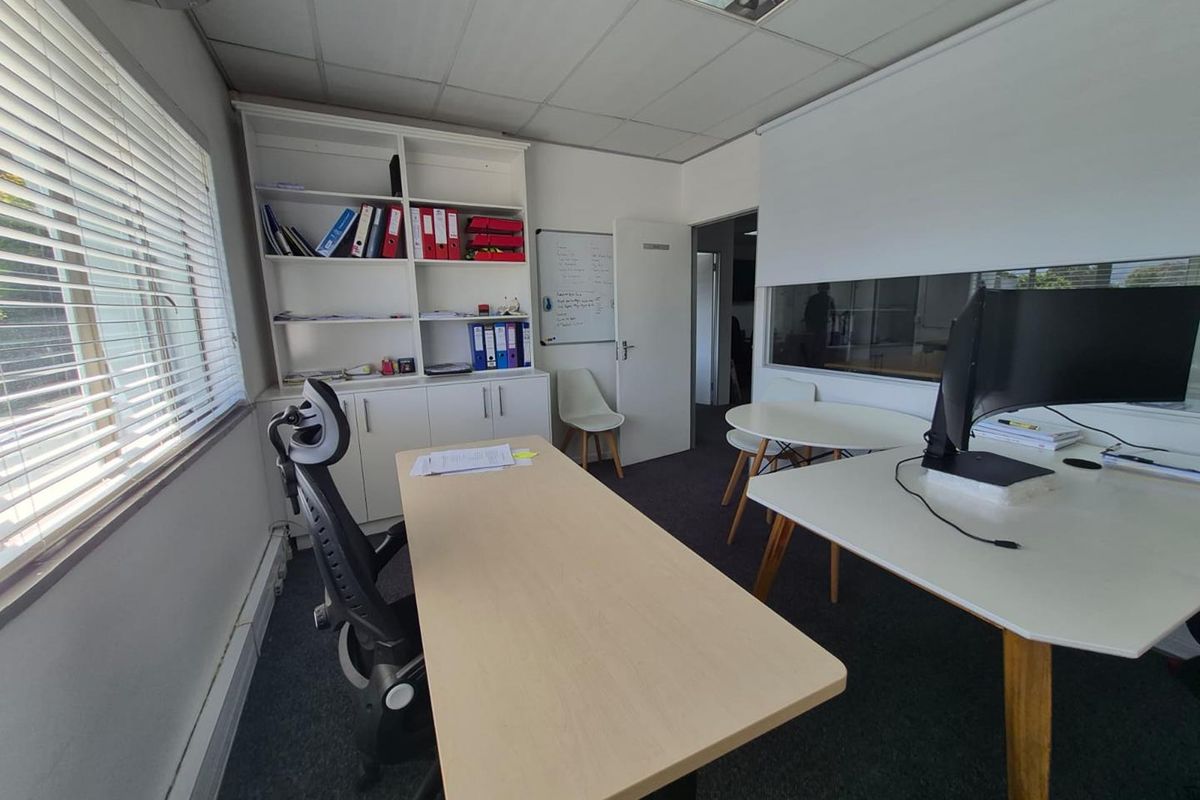 A functional office space featuring built-in shelving, a suspended ceiling, and an internal glass partition, providing a professional work environment.