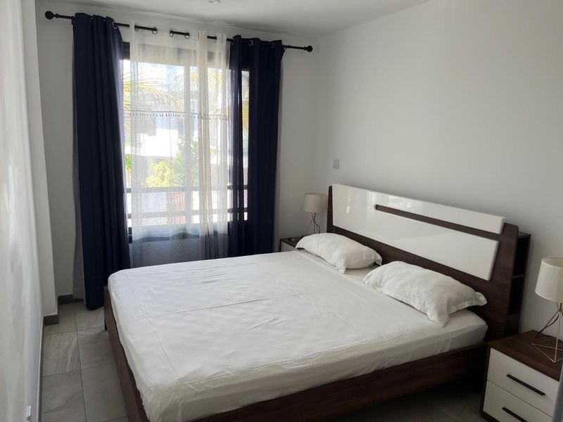 A well-maintained bedroom featuring tiled flooring, recessed ceiling lighting, and a large window allowing natural light.