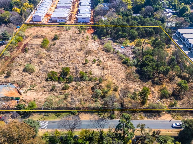 An aerial view of a large, undeveloped residential plot of land, featuring natural vegetation and defined boundary lines.