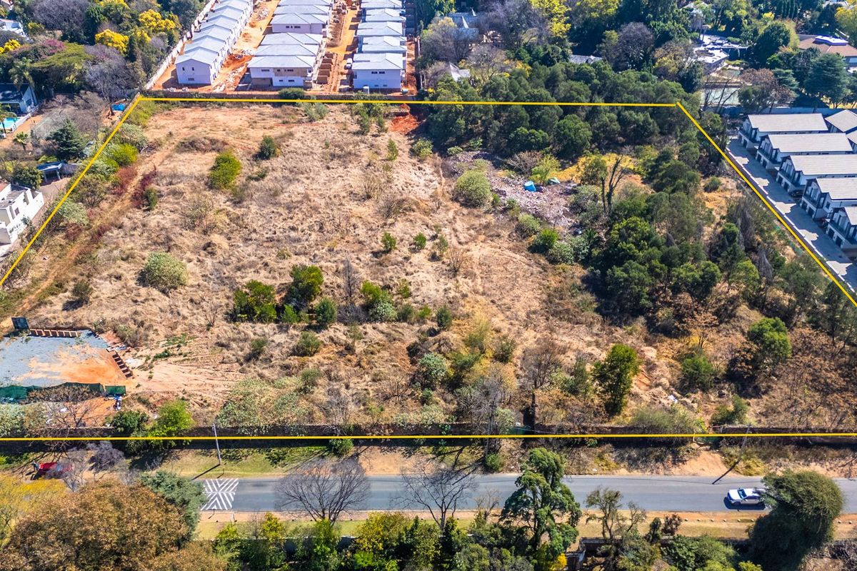 An aerial view of a large, undeveloped residential plot of land, featuring natural vegetation and defined boundary lines.