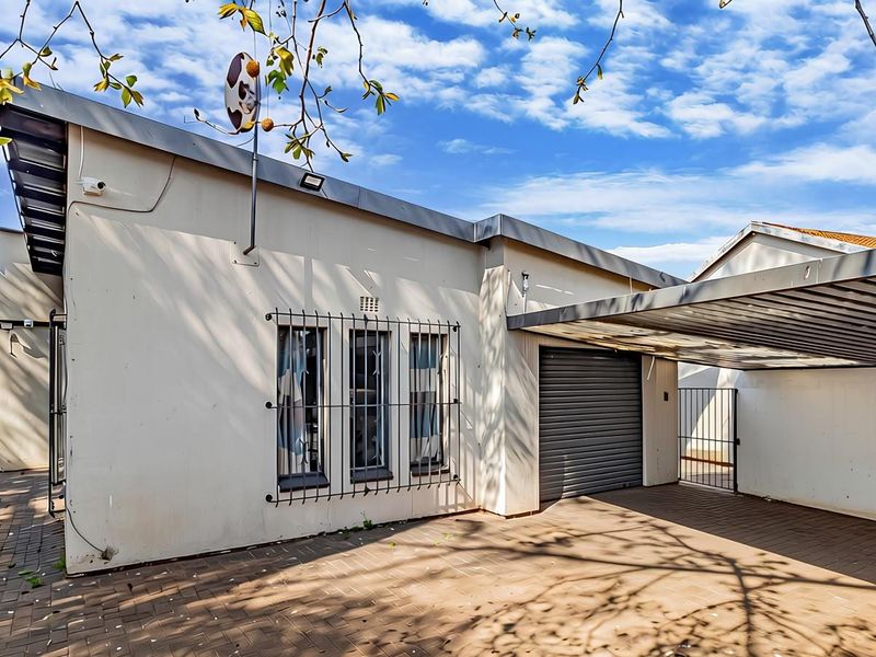 Front exterior view featuring a paved driveway, carport, and a secure garage with a roller shutter door.