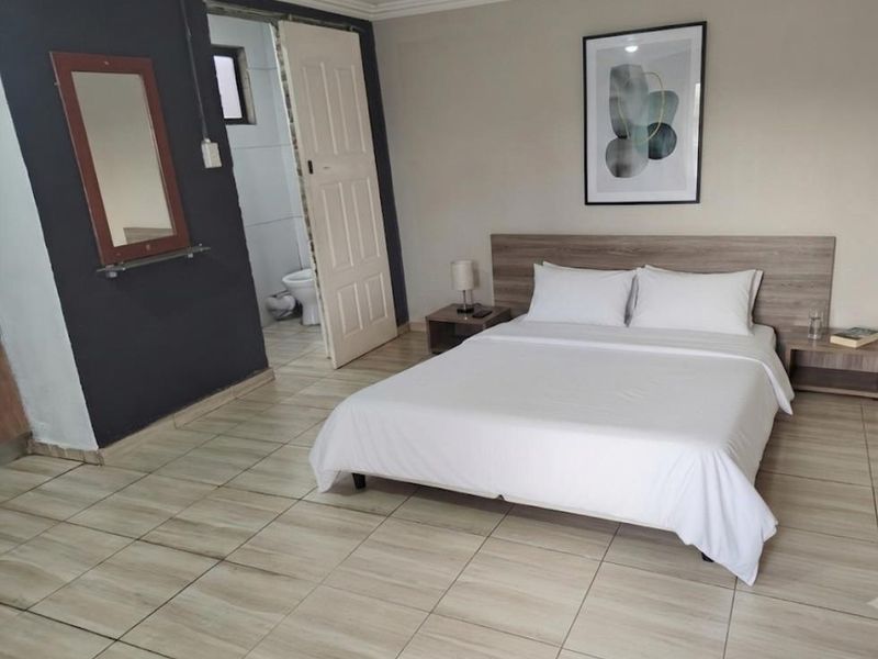 A bedroom featuring tiled flooring, a built-in headboard, and direct access to an en-suite bathroom.