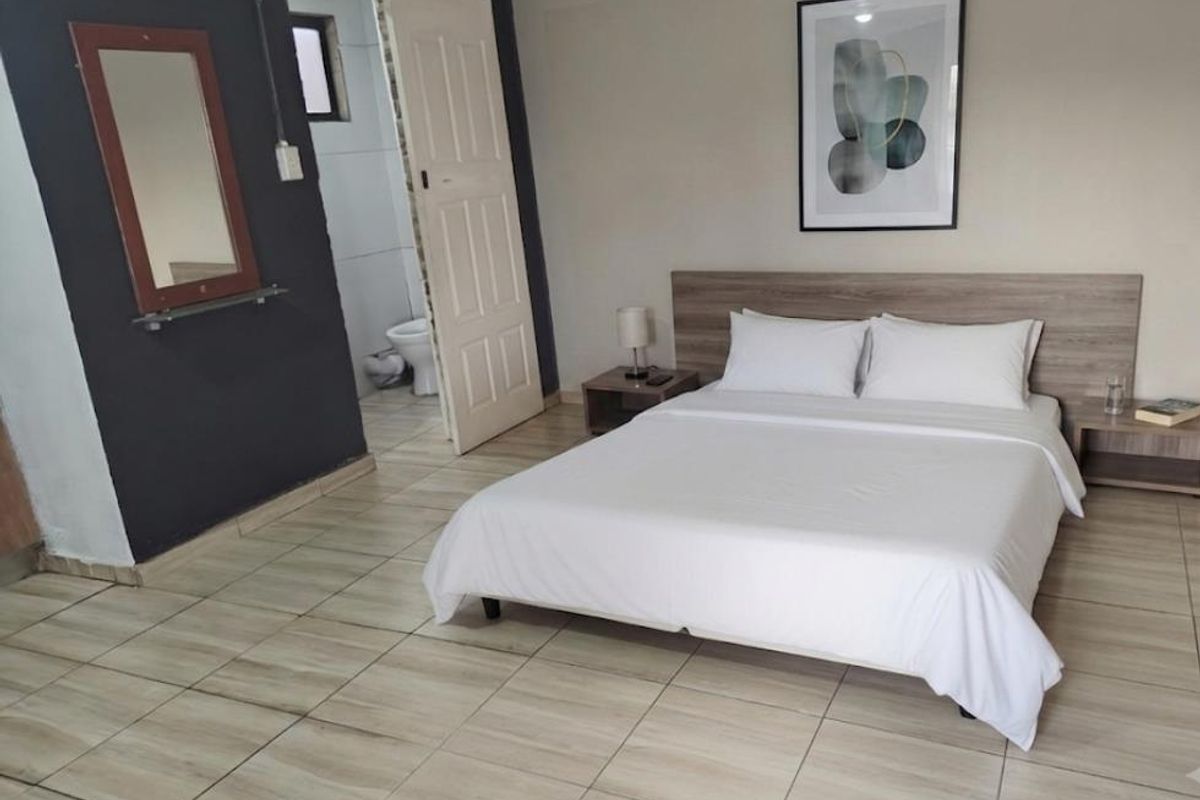 A bedroom featuring tiled flooring, a built-in headboard, and direct access to an en-suite bathroom.