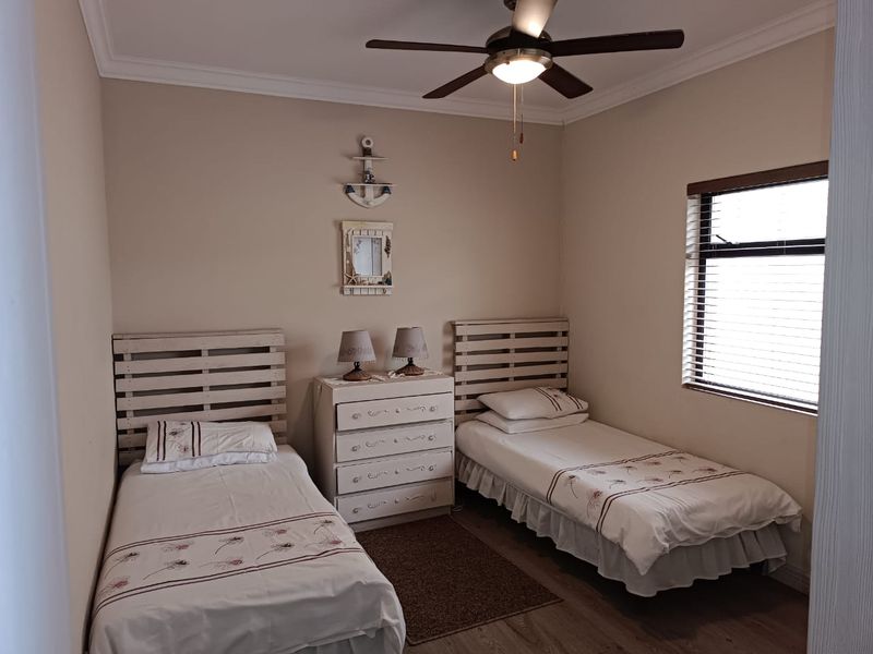 A functional bedroom featuring laminate flooring, a ceiling fan, and venetian blinds, providing a comfortable and well-lit space.