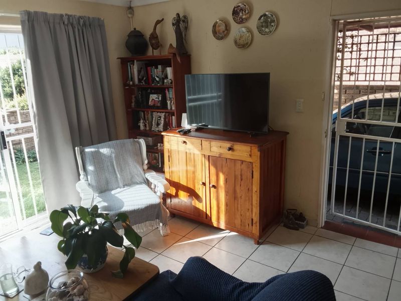 A living room area featuring tiled flooring, a sliding glass door leading to the exterior, and a security gate at the entrance.