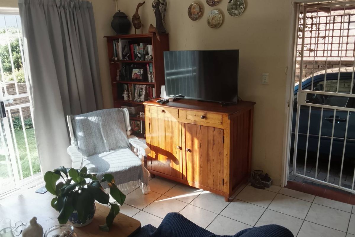 A living room area featuring tiled flooring, a sliding glass door leading to the exterior, and a security gate at the entrance.